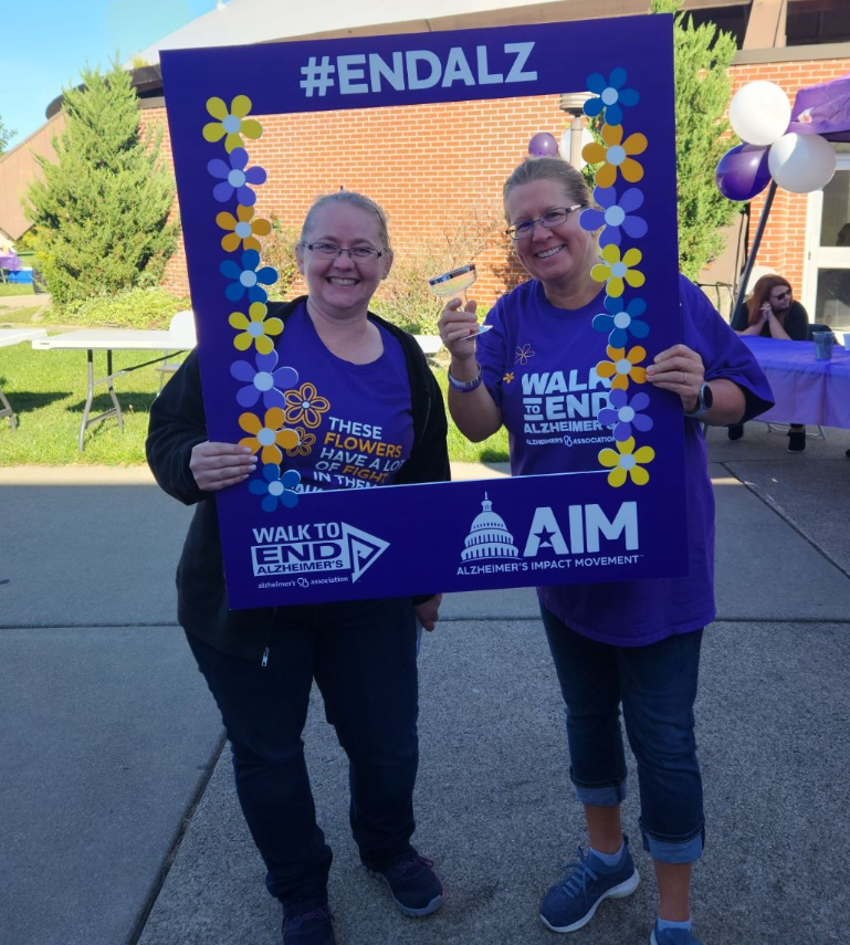 Two Oak Hill female employees wearing purple End Alzheimers shirts pose for a photo